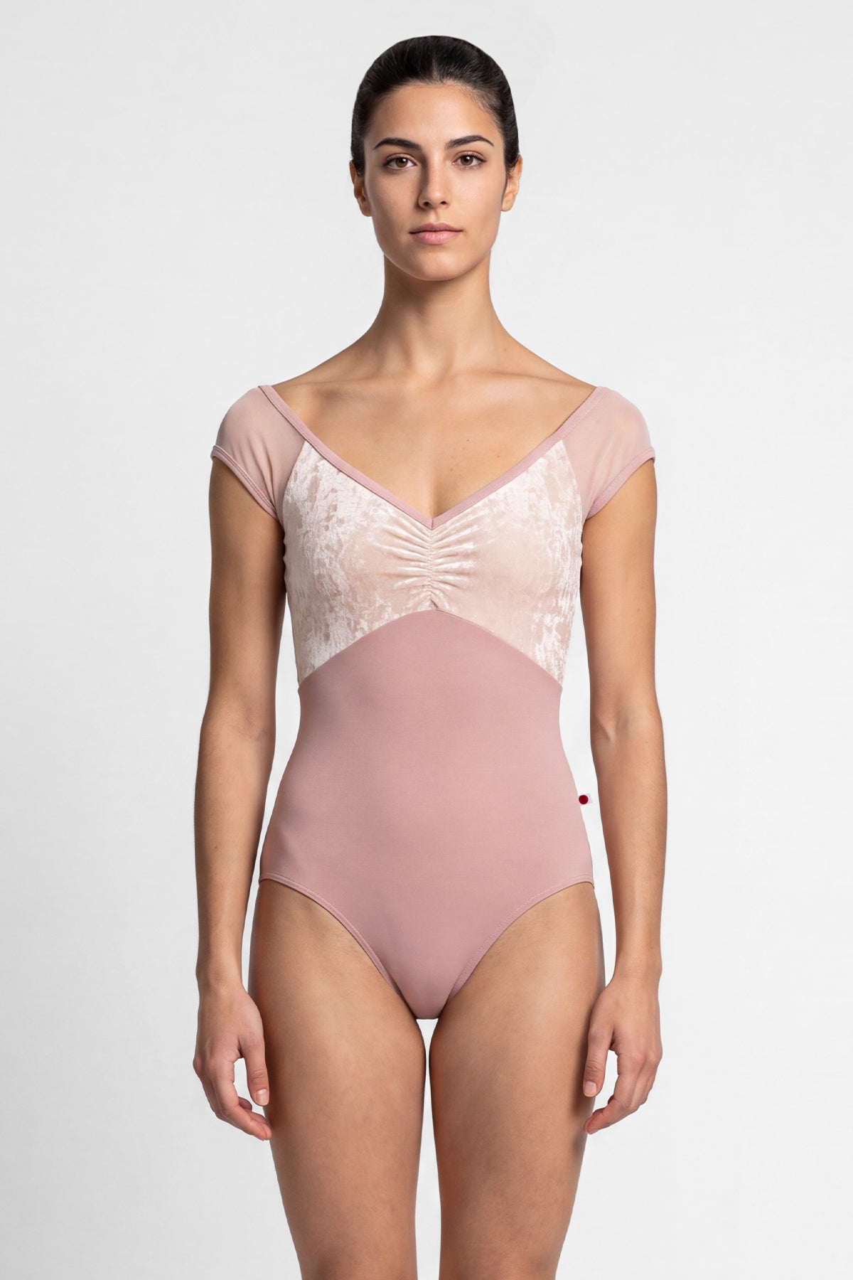 AI-generated model. Elli leotard, dusty-rose with a cream crushed-velvet ruched bust and blush mesh cap sleeves, V-neck.