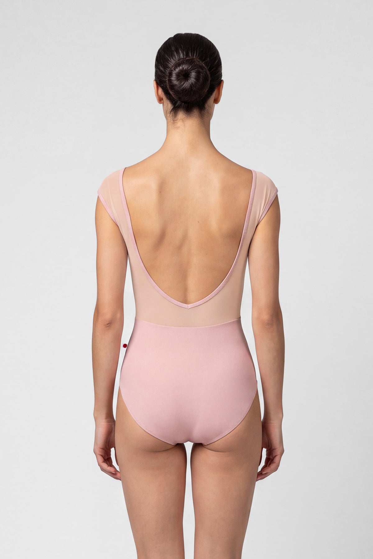 AI-generated model. Elli leotard, dusty-rose with a cream crushed-velvet ruched bust and blush mesh cap sleeves, V-neck.