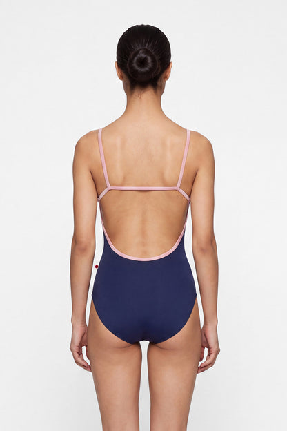 AI-generated model. Tamara leotard, navy with a scoop neck and pink strap and neckline trim.