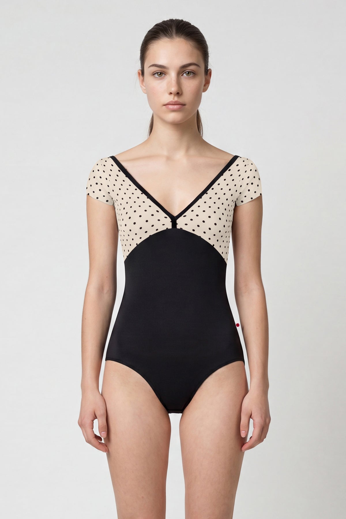 AI-generated model. Alicia leotard, cream polka-dot cap-sleeve bodice with black V-neck trim and black body.