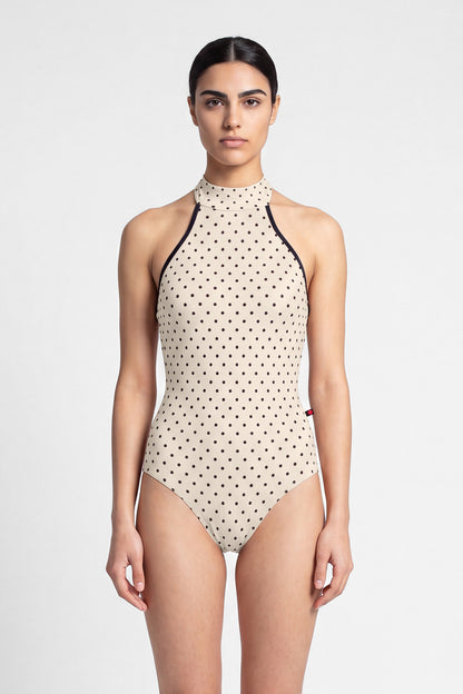 AI-generated model. Kelly leotard, all-over T-Lunares Cream polka-dot with a black-trimmed high halter neck and open sides.
