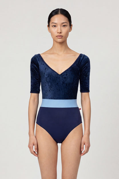 AI-generated model. Lucy leotard, navy crushed-velvet elbow-sleeve bodice with a light-blue waistband and a navy body, V-neck.