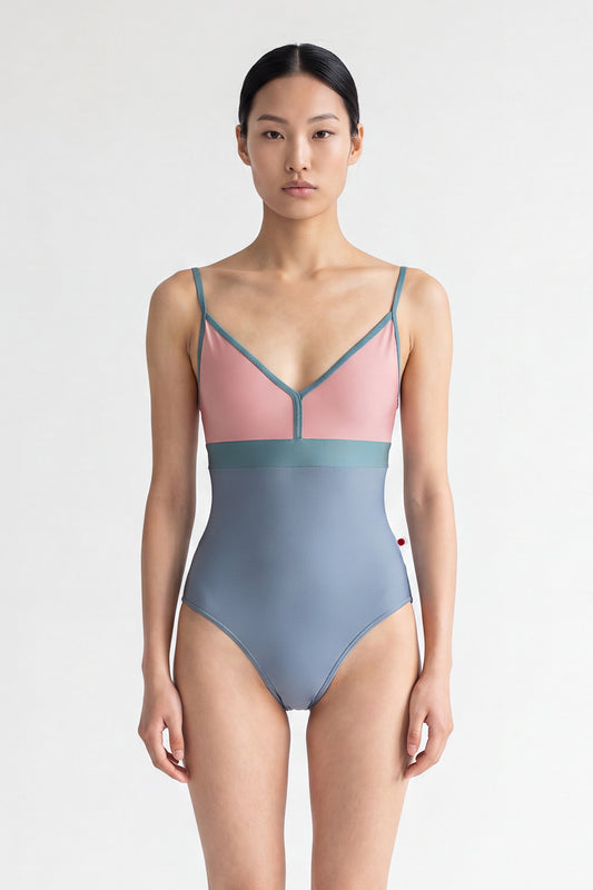 AI-generated model. Zoe leotard, dusty-rose bust and blue-grey body with a teal waistband and thin teal straps, V-neck.