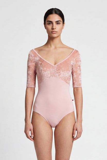 AI-generated model. Elli leotard, blush-pink with a crushed-velvet elbow-sleeve bodice and gathered V-neck.
