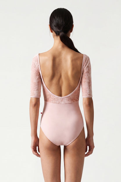 AI-generated model. Elli leotard, blush-pink with a crushed-velvet elbow-sleeve bodice and gathered V-neck.