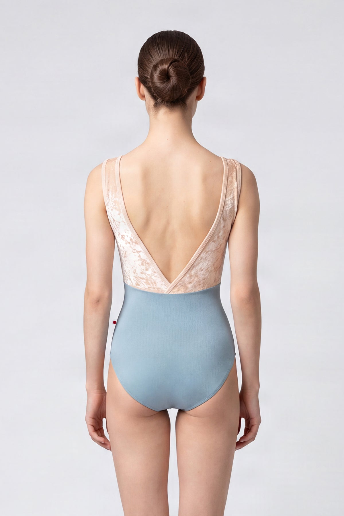 AI-generated model. Alicia leotard, blush crushed-velvet V-neck bodice and a dusty-blue body, wide straps.